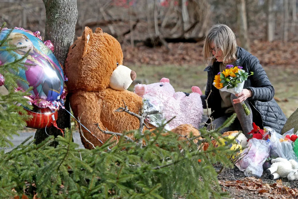 A woman lays flowers down at a makeshift memorial in front of 47 Summer Street on January 26, 2023 in Duxbury, Massachusetts.